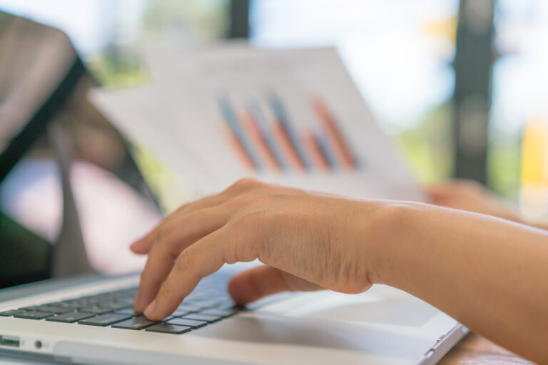 Business woman hand with Financial charts and laptop on the tabl